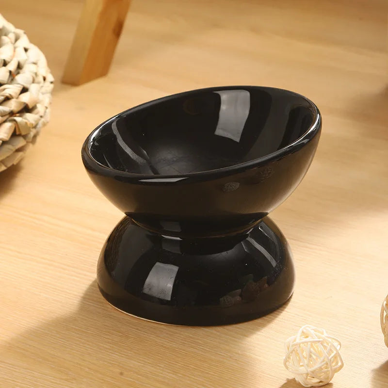 Tilted Ceramic Cat Bowl in Black — angled bowl on a wooden tabletop