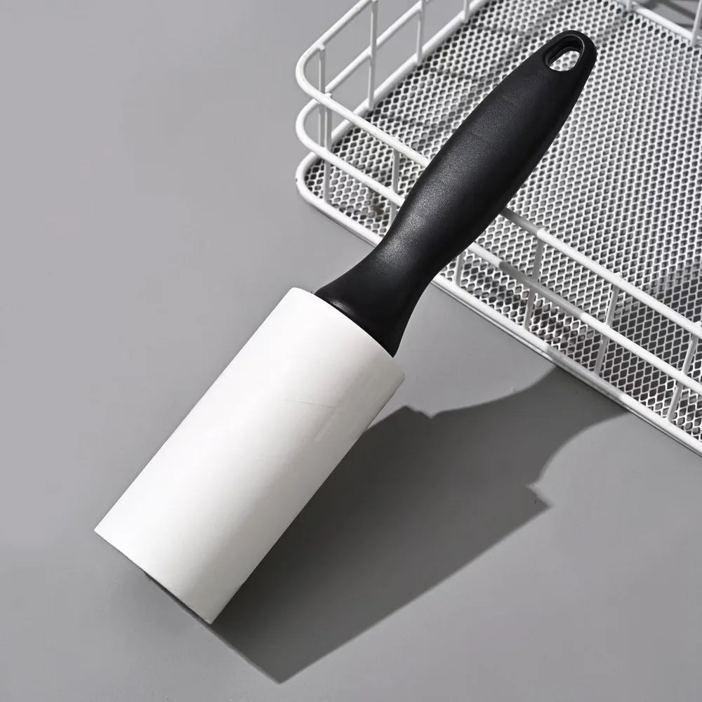 Pet Hair Lint Roller in Black — roller resting on a grey surface beside a wire basket